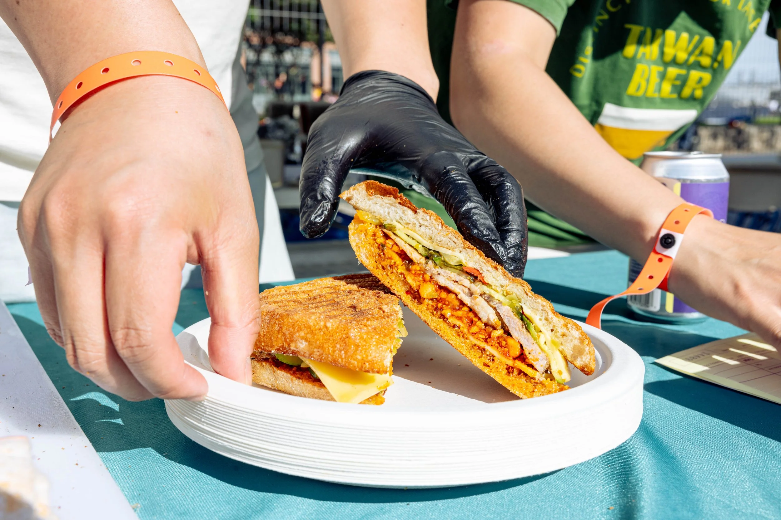 A person holding a half-eaten bao bun with filling, at an outdoor event or festival.