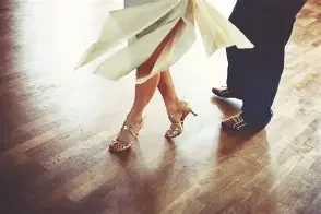 Détails des jambes et des pieds de deux personnes dansant, avec un sol en bois.