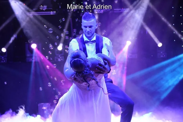 Un homme et une femme dans un costume de soirée, avec une femme enceinte, sous des lumières colorées et des bulles, lors d'une scène de spectacle ou de performance