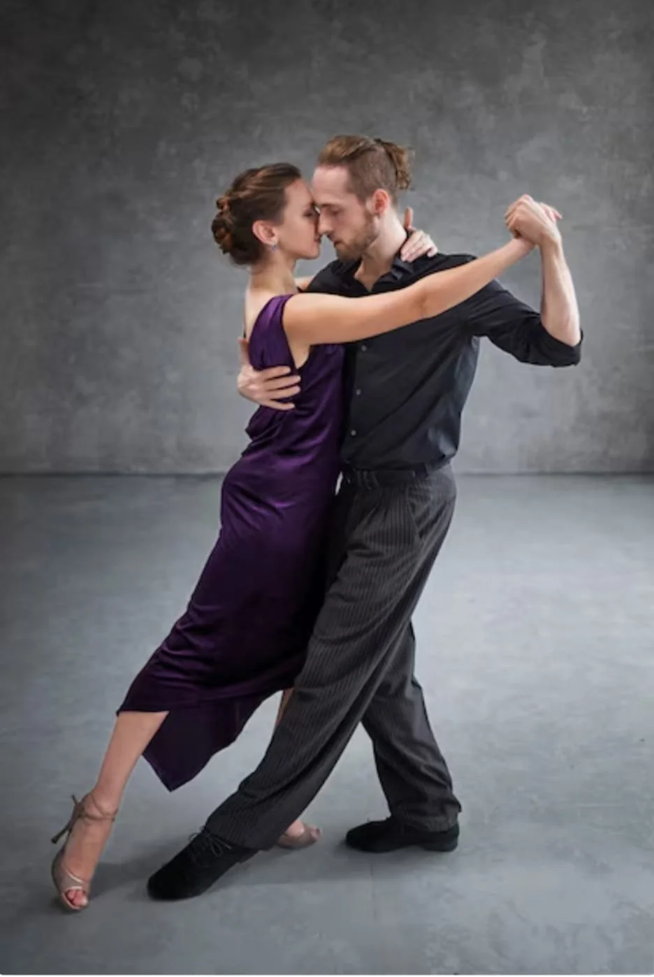 Un couple danseur de tango argentin, son visage proche, la femme en robe violette et le homme en chemise noire, dans une pose de danse.