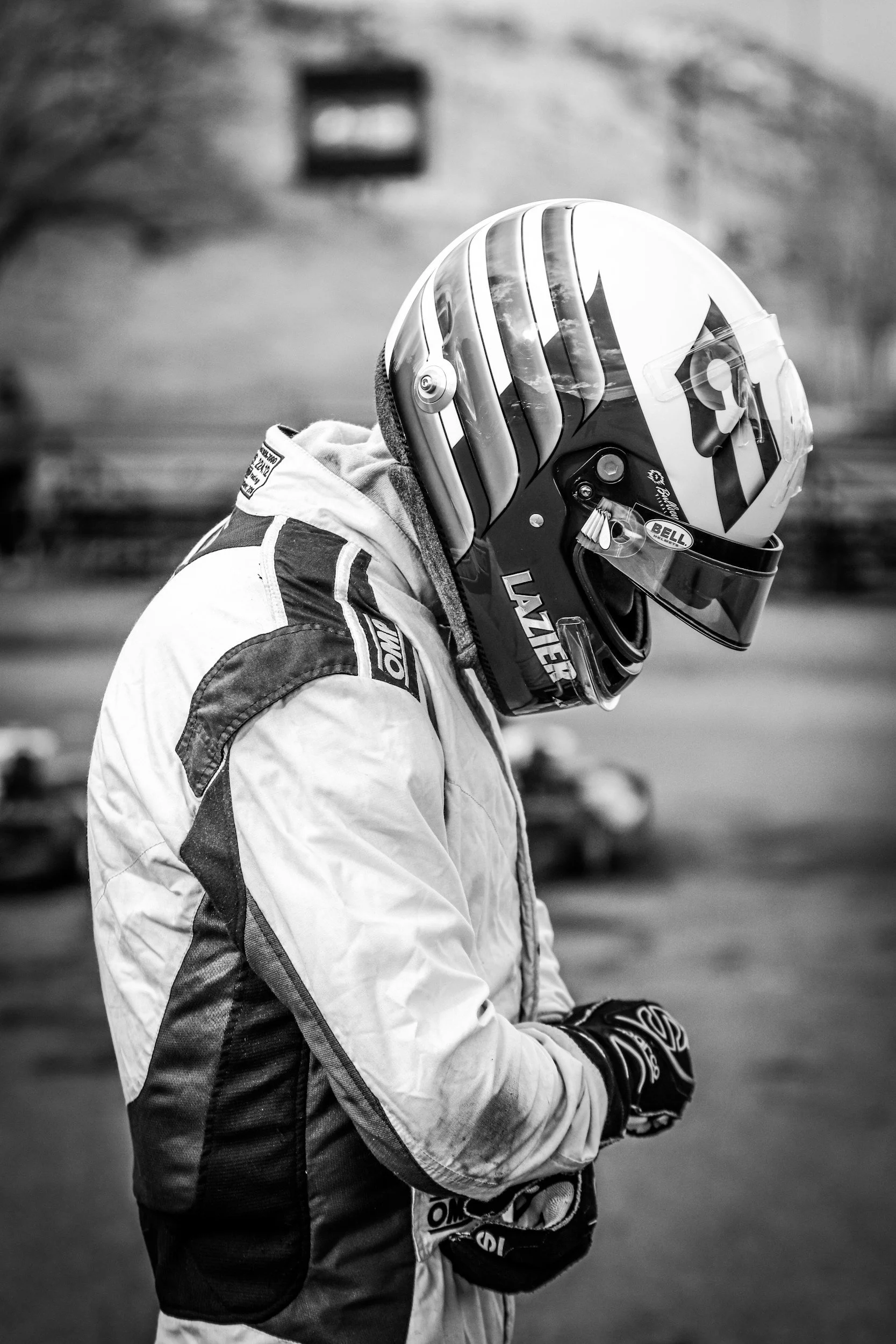 A person dressed in racing gear wearing a helmet and jacket, standing outdoors.