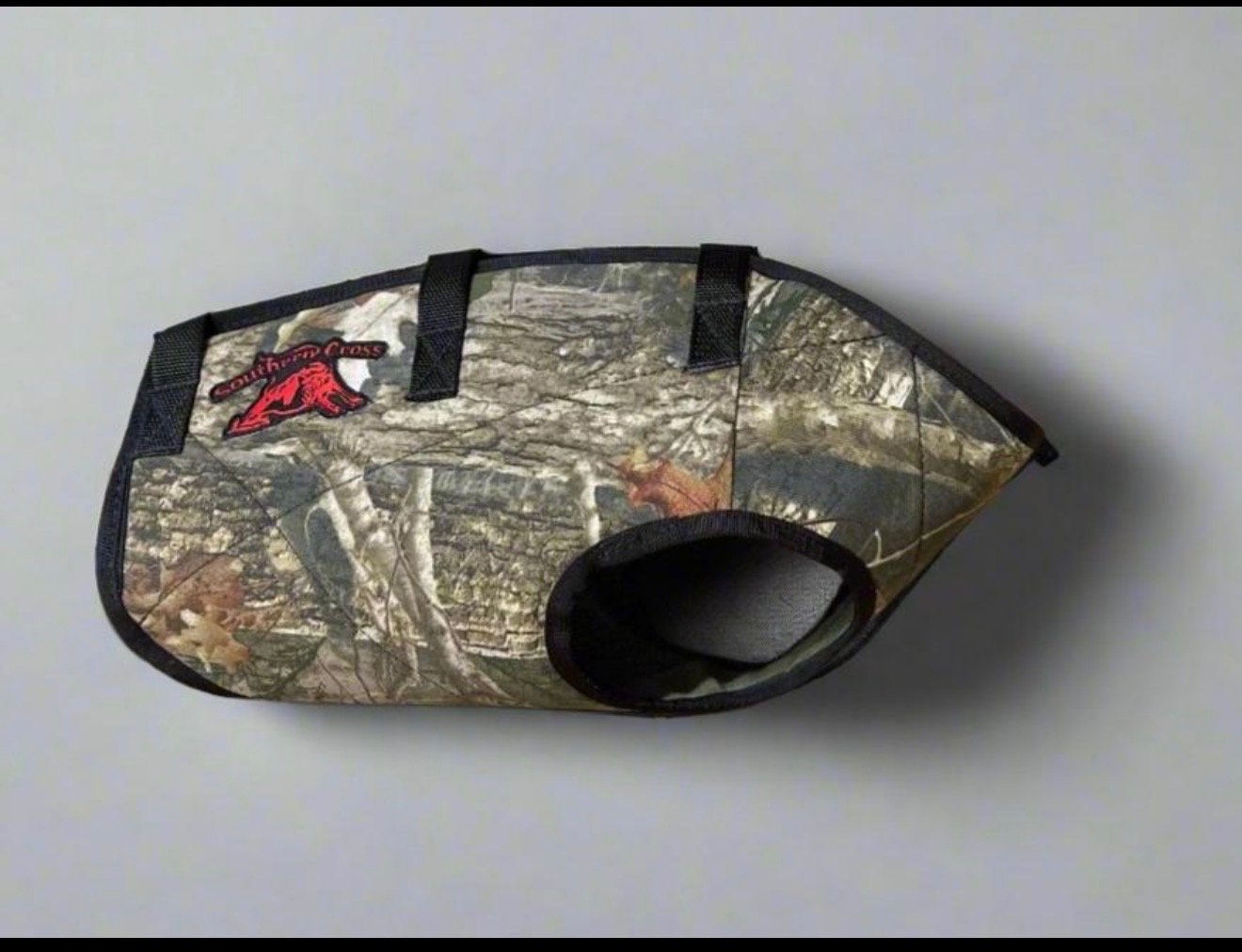 Camouflage dog muzzle with North America Cross logo on a plain gray background.