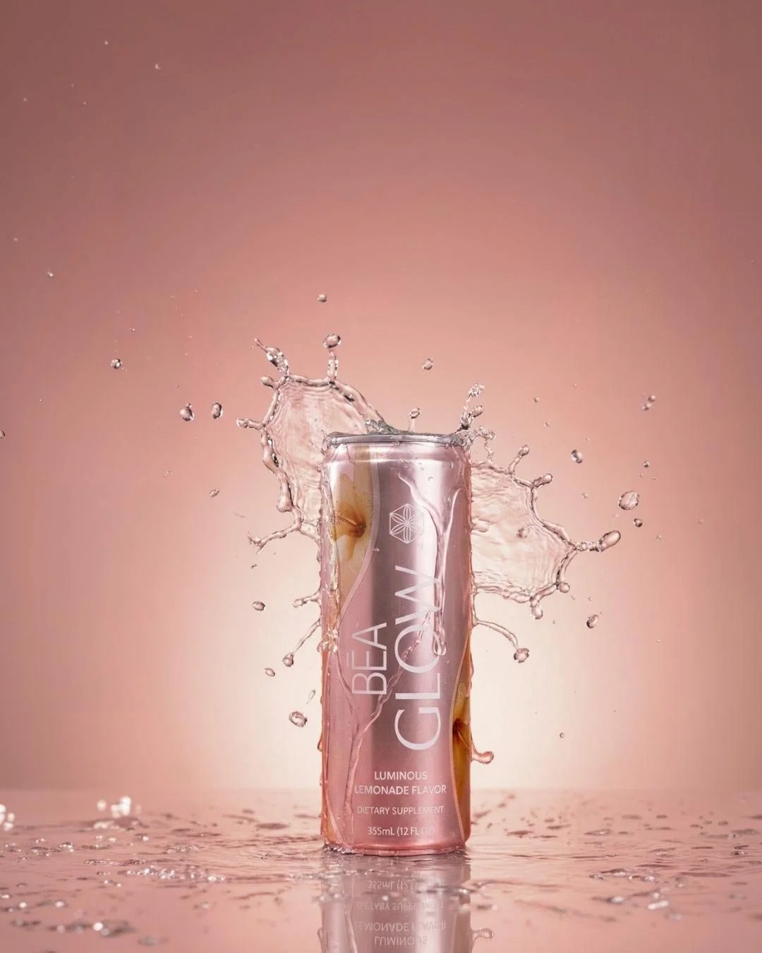A can of Bea Cl&aring;v Luminous Lemonade Flavor sparkling beverage splashing with water against a pink background.
