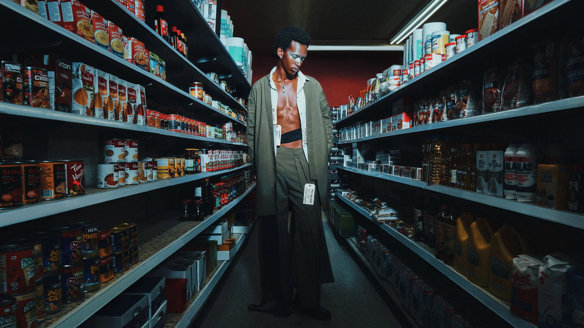 Model in a kimono jacket standing in a lit convenience store aisle wearing a price tag, editorial fashion photography by Philippe Manh