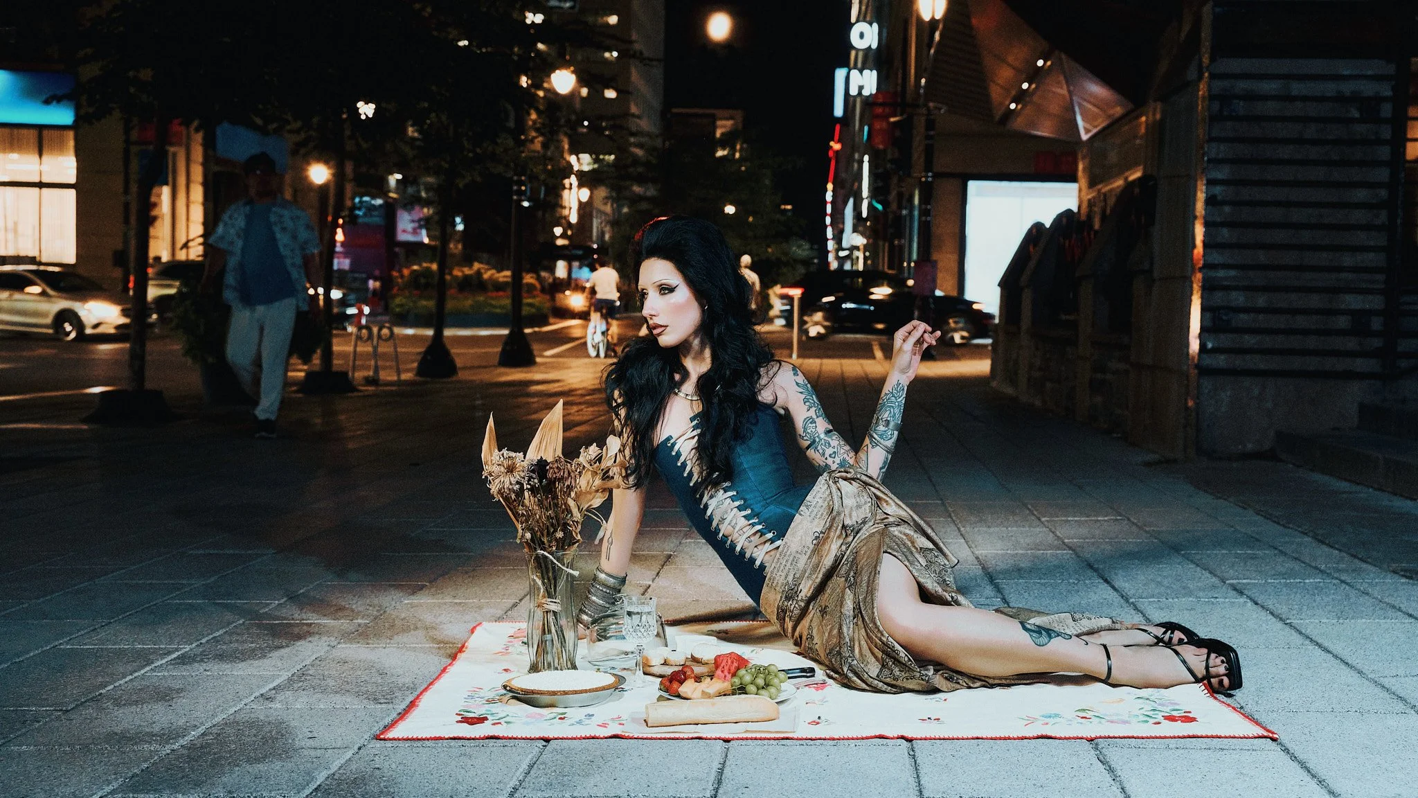 Fashion model reclining on a picnic blanket set on a downtown Montreal sidewalk at night, from the series MISCONDUCT