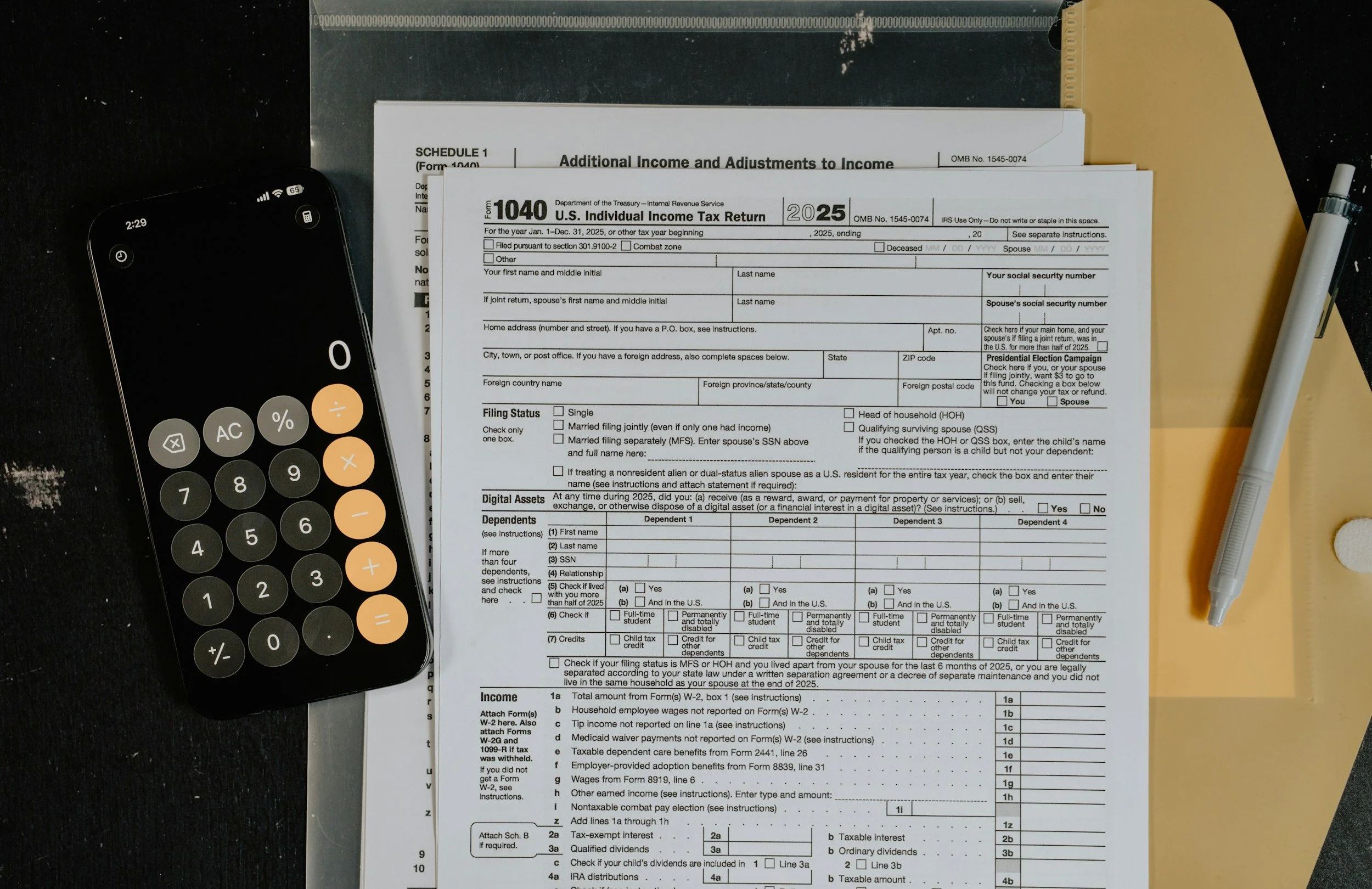 U.S. IRS tax form 1040 for the year 2025, placed on top of a yellow folder, with a black calculator and a white pen nearby, on a black surface.