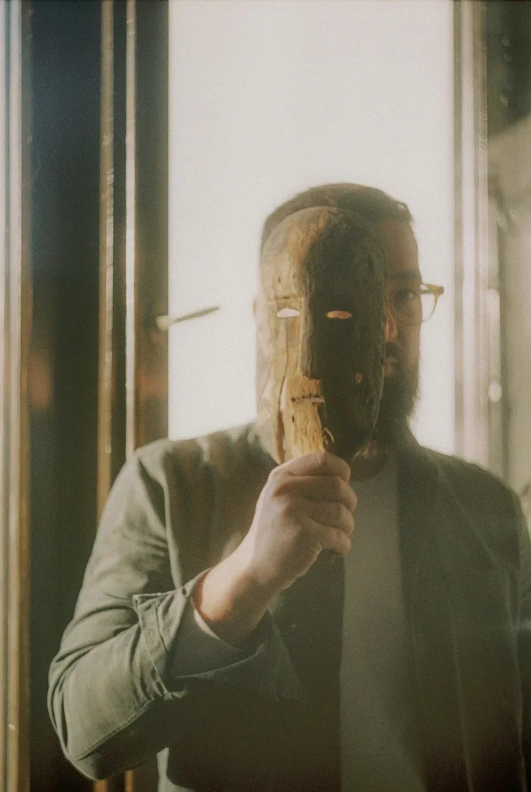 Personne tenant un masque de bois devant son visage