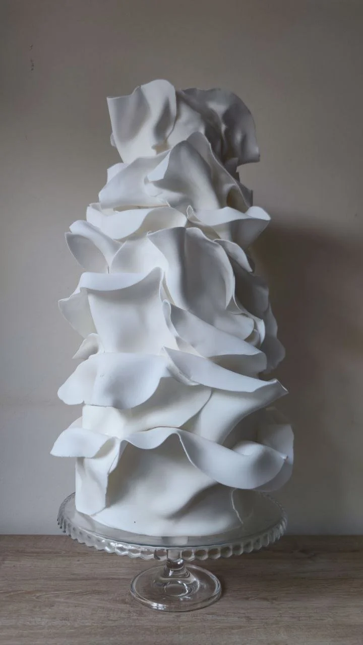Elegant white wedding cake with lace and ruffled draping