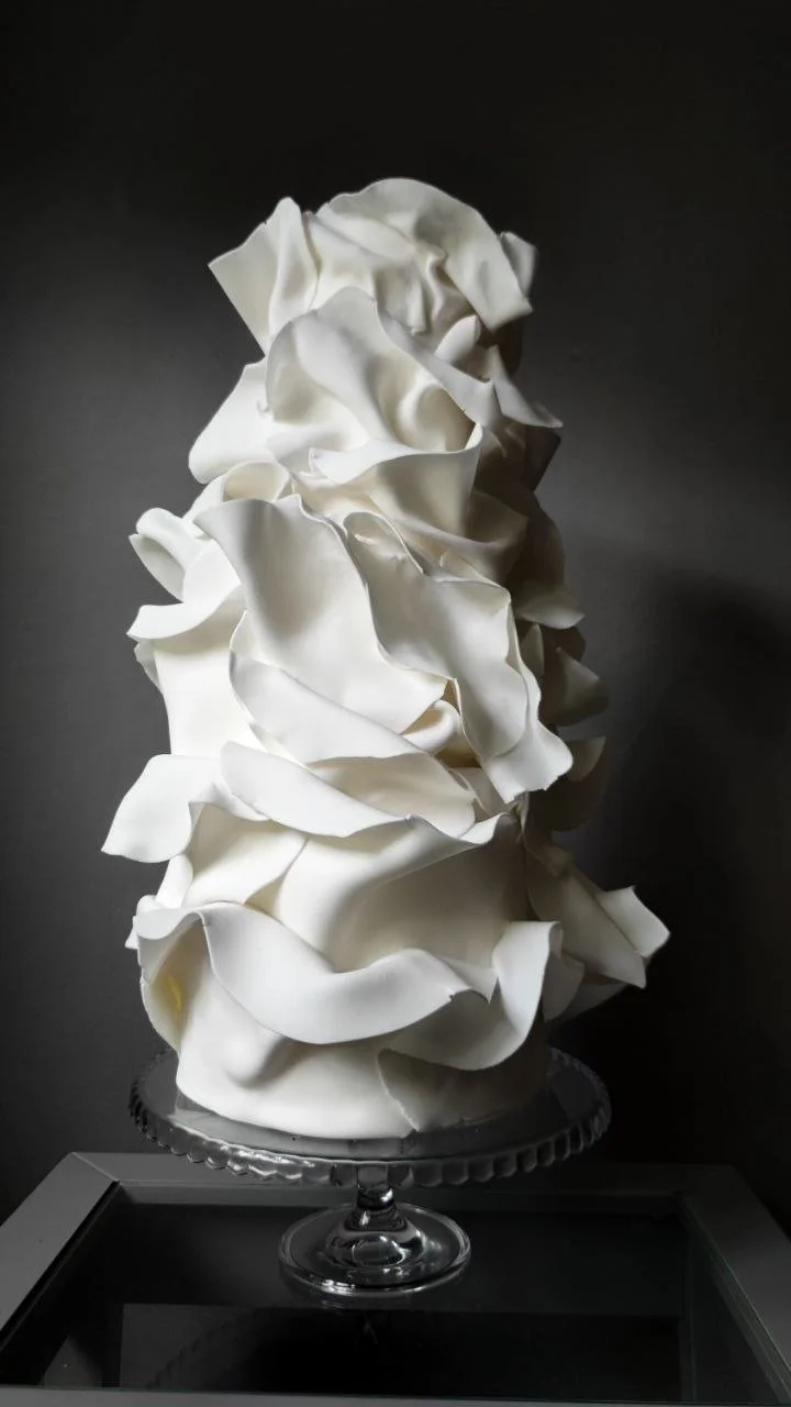 Contemporary white wedding cake with an abstract sculptural design and dramatic flowing forms.