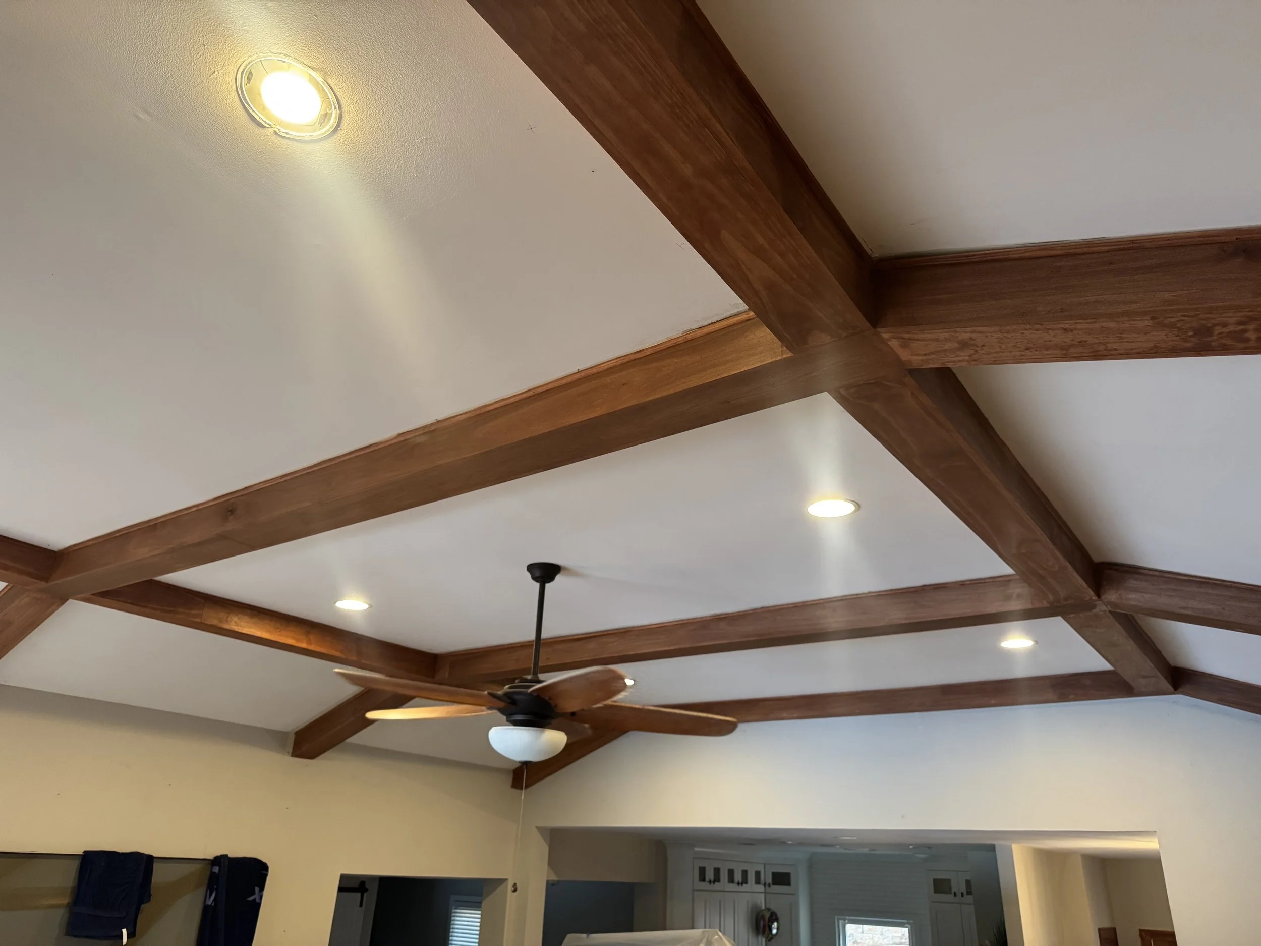 Ceiling with wooden beams, recessed lighting, and a ceiling fan in a living room.