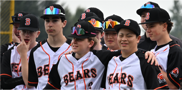 Group of young baseball players in team uniforms and caps, some wearing sunglasses, standing together outdoors.