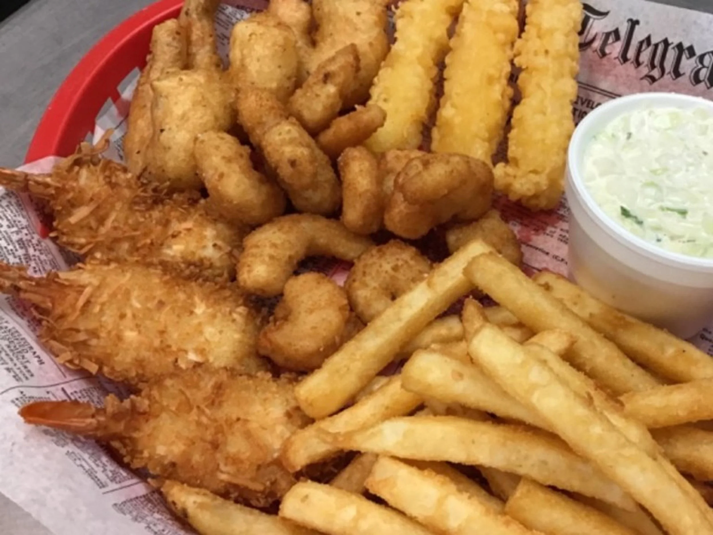 A basket of fried fish filets, French fries, and a side of coleslaw.