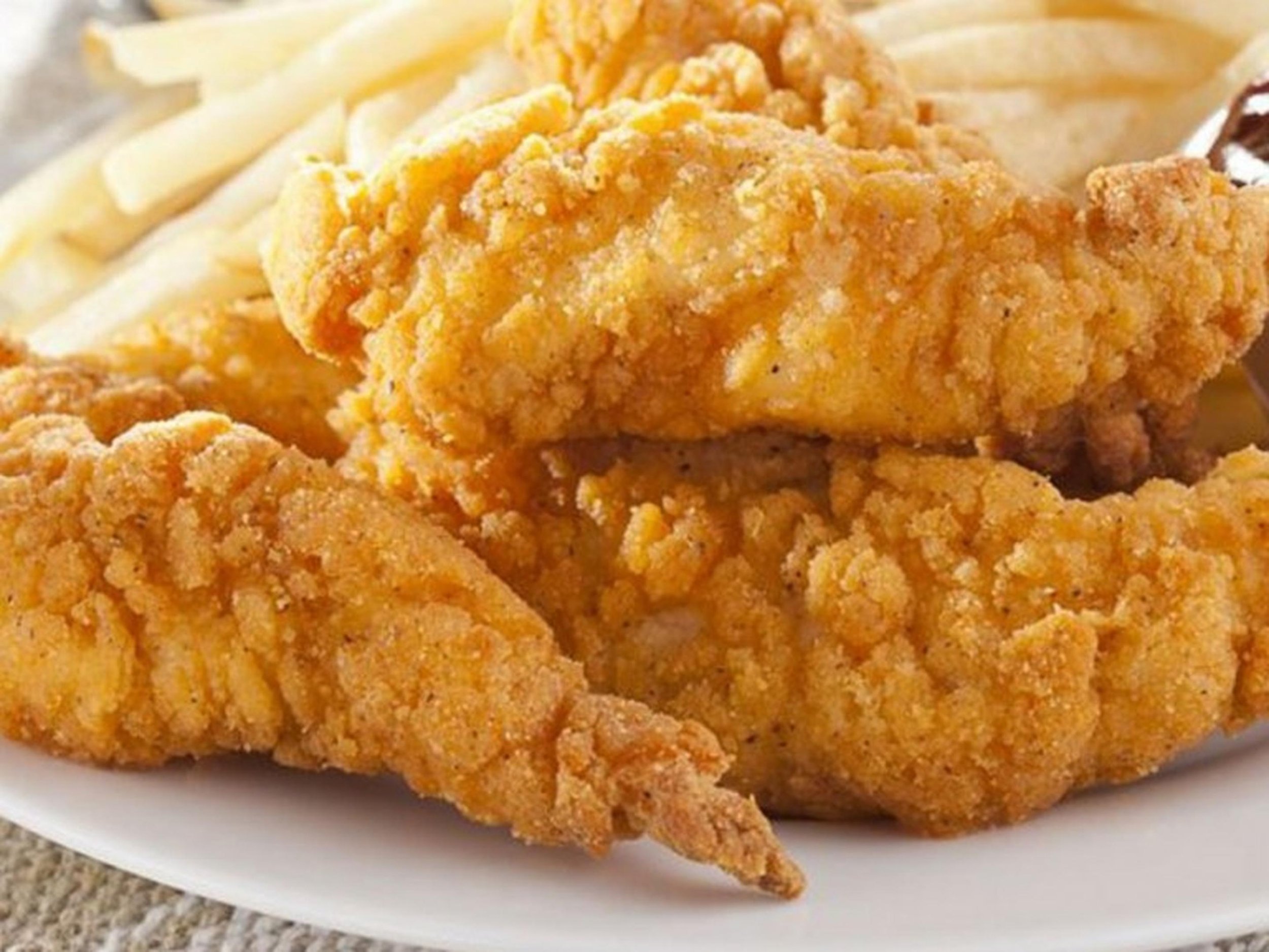 Close-up of a plate with crispy fried chicken tenders and French fries.