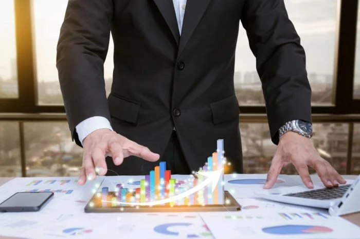 Businessperson in formal suit analyzing digital bar chart on tablet in office