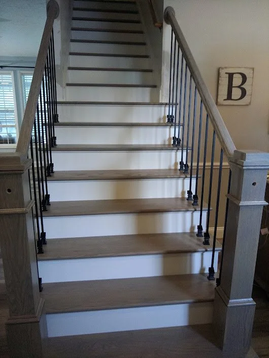 Wooden staircase with metal balusters and wooden steps leading upstairs in a house.
