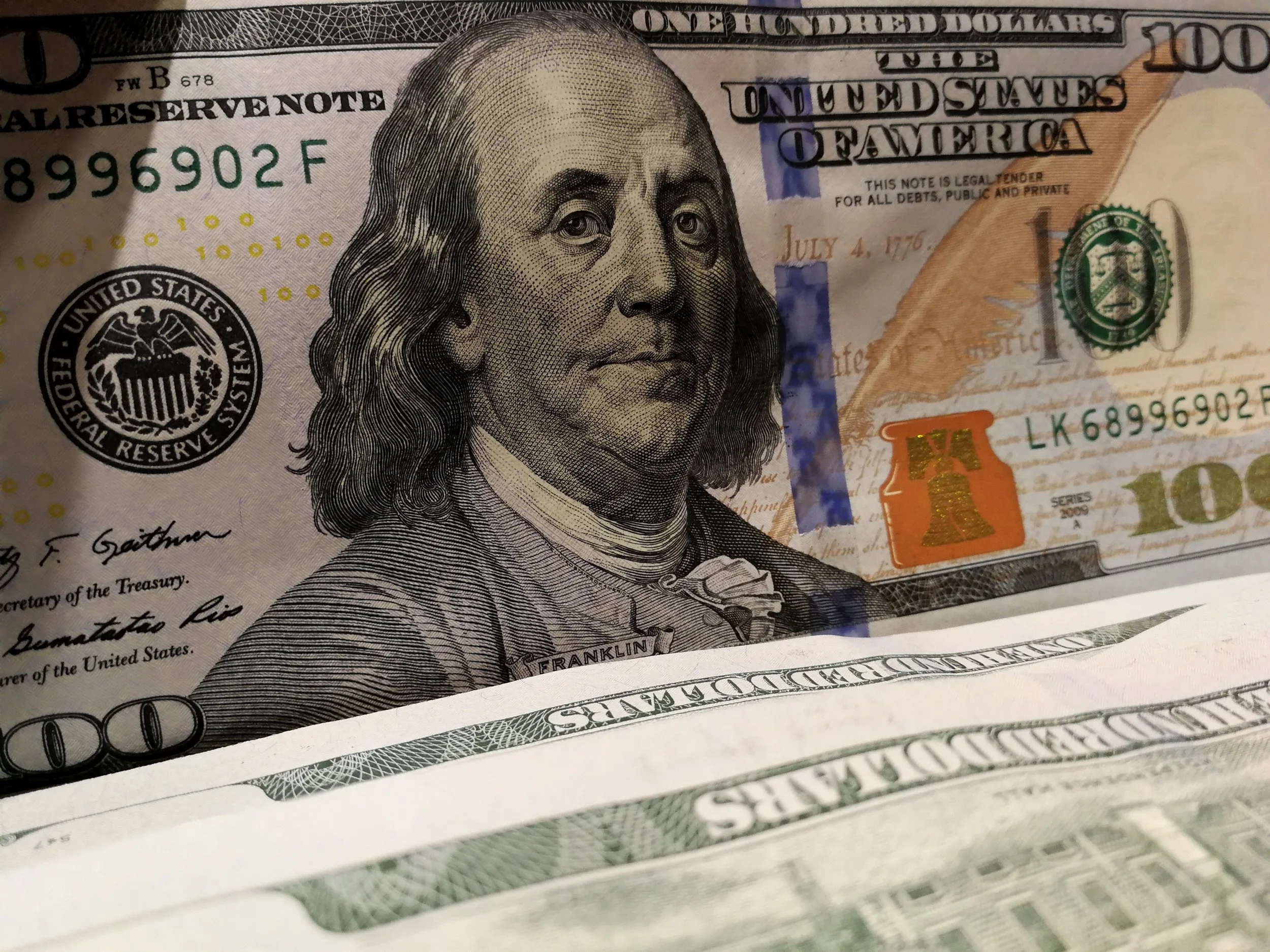 Close-up of a one hundred dollar bill featuring Benjamin Franklin's portrait.
