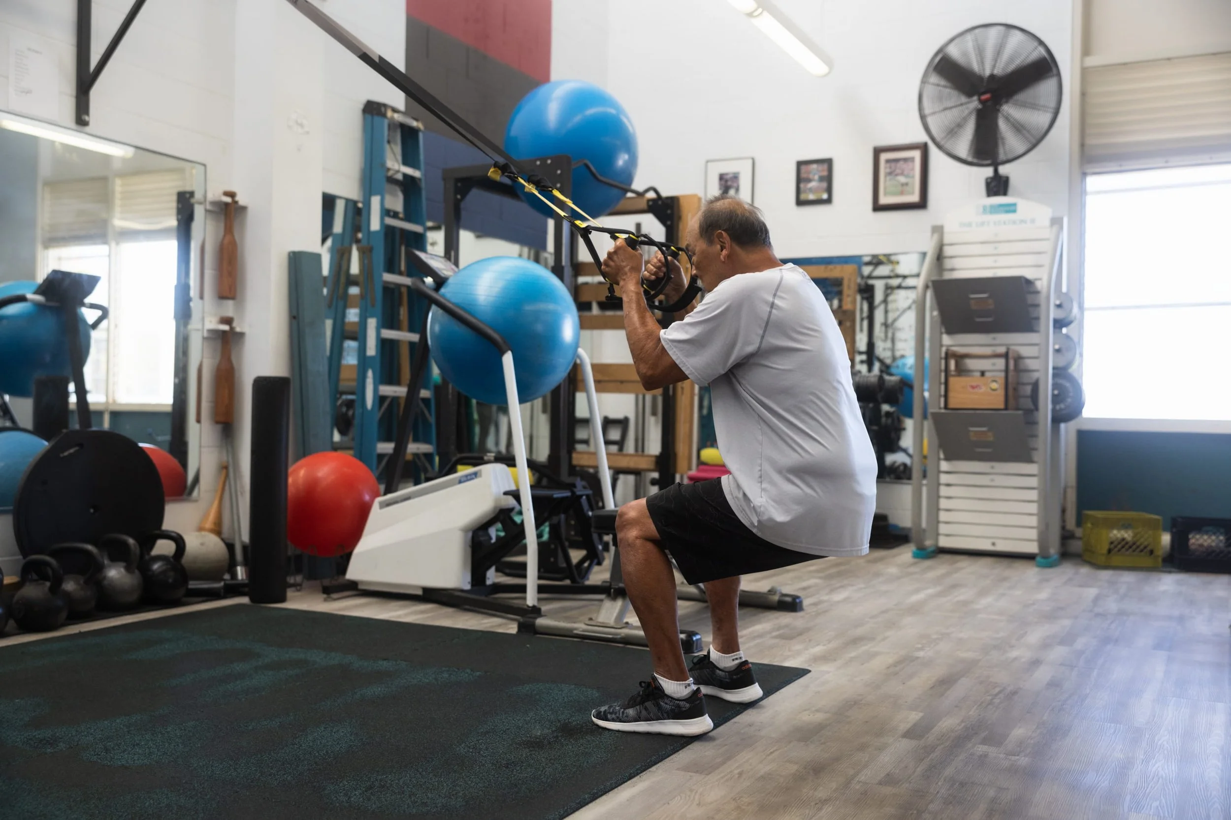 A patient trains on TRX equipment in the well-equipped W.O.R.C. gym at Fukuji & Lum's Kaneohe location.