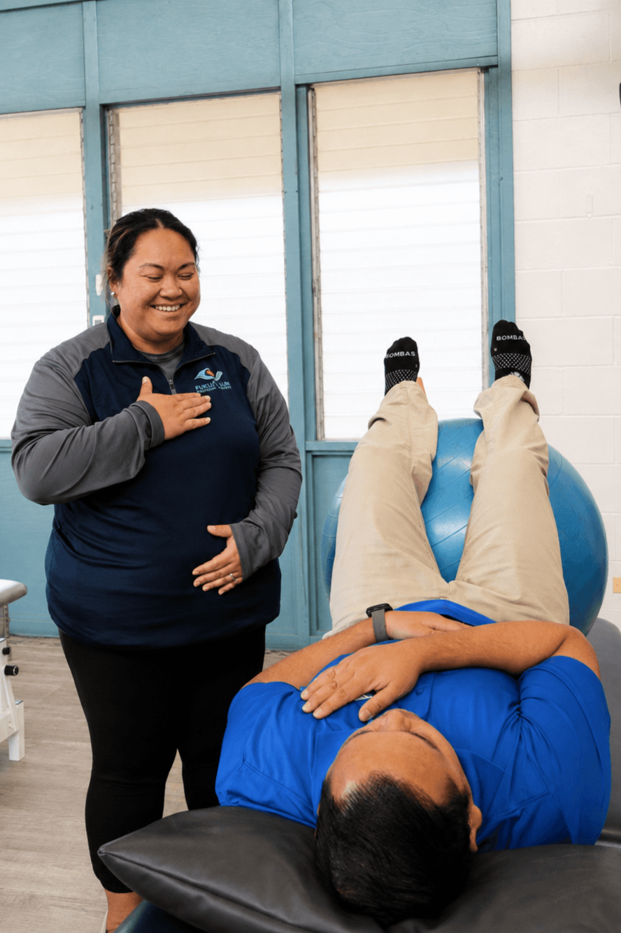 A Fukuji & Lum pelvic health therapist smiles while guiding a patient through a supported exercise during a treatment session.