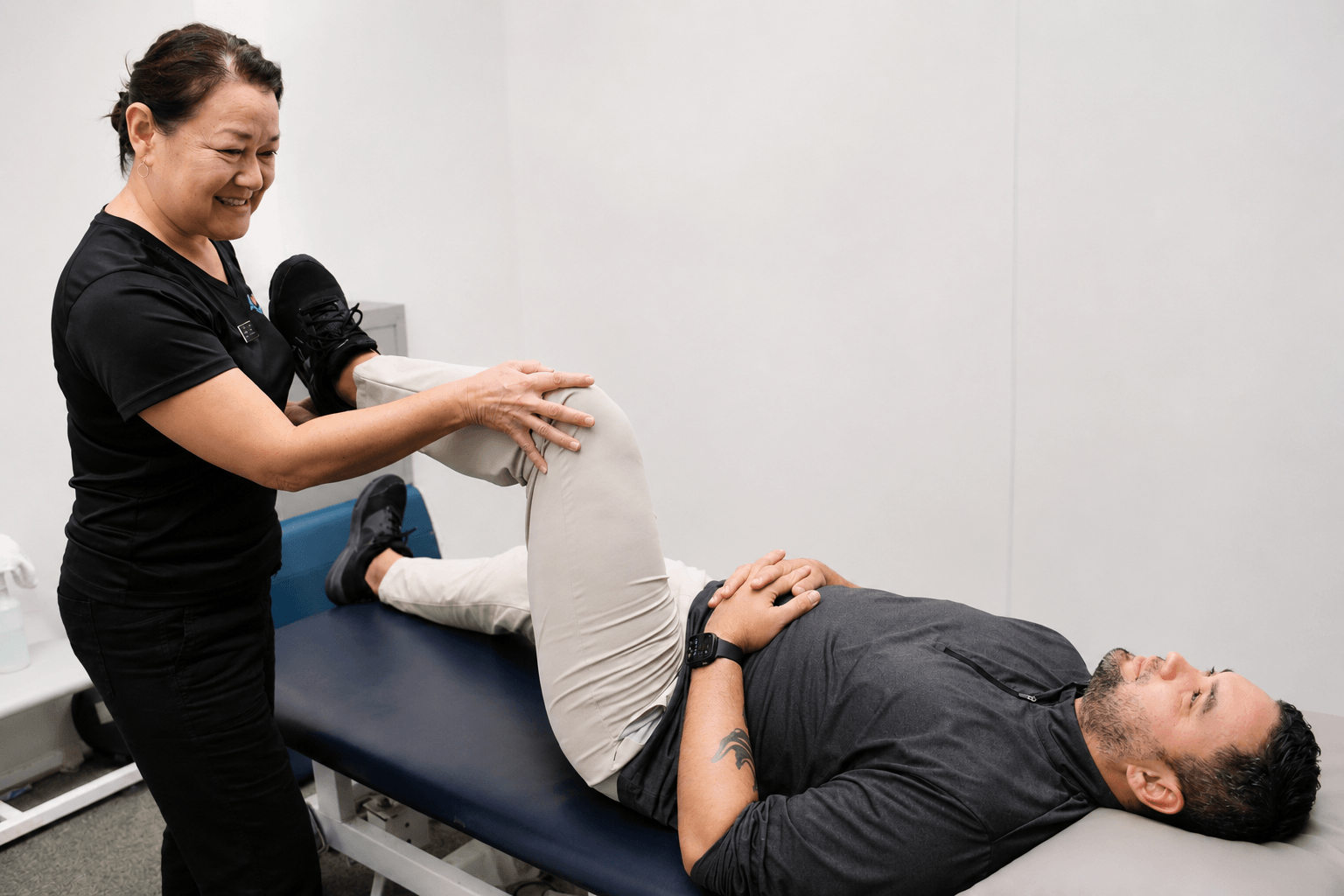 A Fukuji & Lum physical therapist guides a patient through a knee and hip mobility exercise during a one-on-one session.