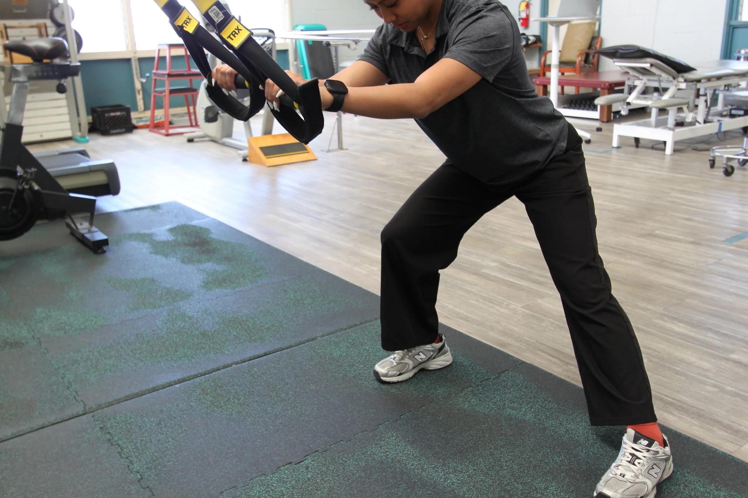 A patient performs a TRX suspension exercise to rebuild upper-body and core strength during occupational rehab at Fukuji & Lum's W.O.R.C. center.
