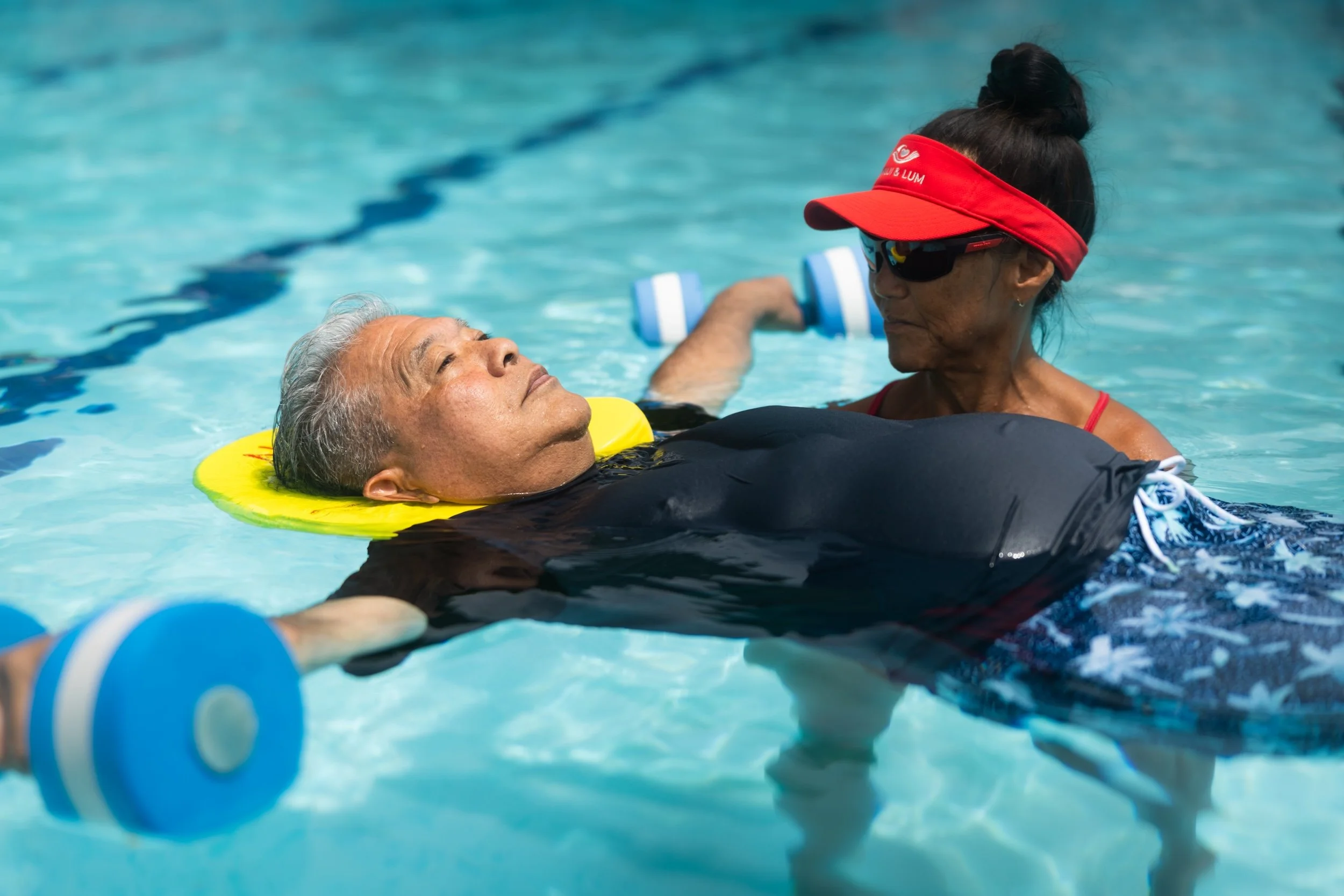 A Fukuji & Lum therapist supports a patient as he floats and exercises with water dumbbells.