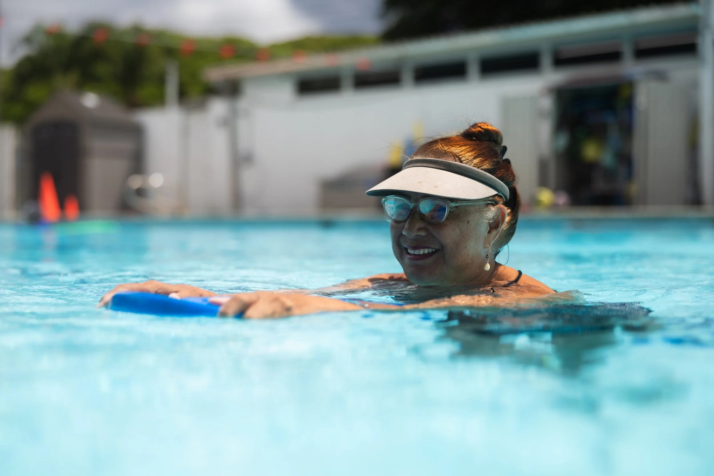 An older adult smiles while exercising in Fukuji & Lum's outdoor heated therapy pool in Kaneohe.