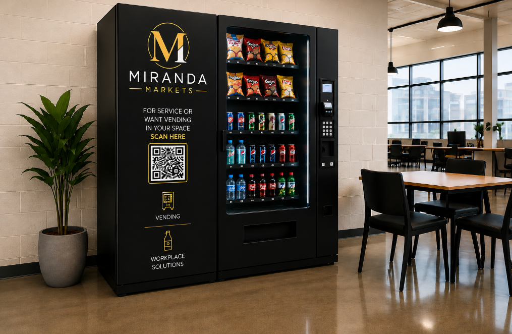 Vending machine branded Miranda Markets with snacks and beverages inside, located in a modern office space with tables and chairs, a potted plant to the side, and large windows in the background.