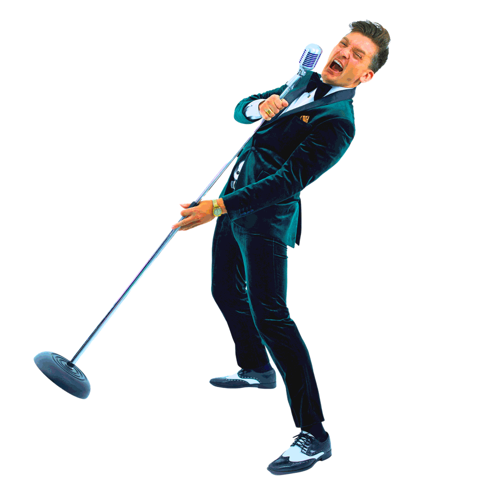 A man in a tuxedo singing passionately into a vintage-style microphone.
