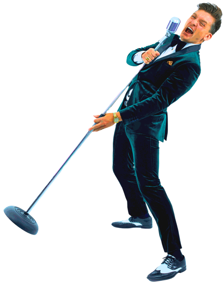 A man in a tuxedo passionately singing into a microphone
