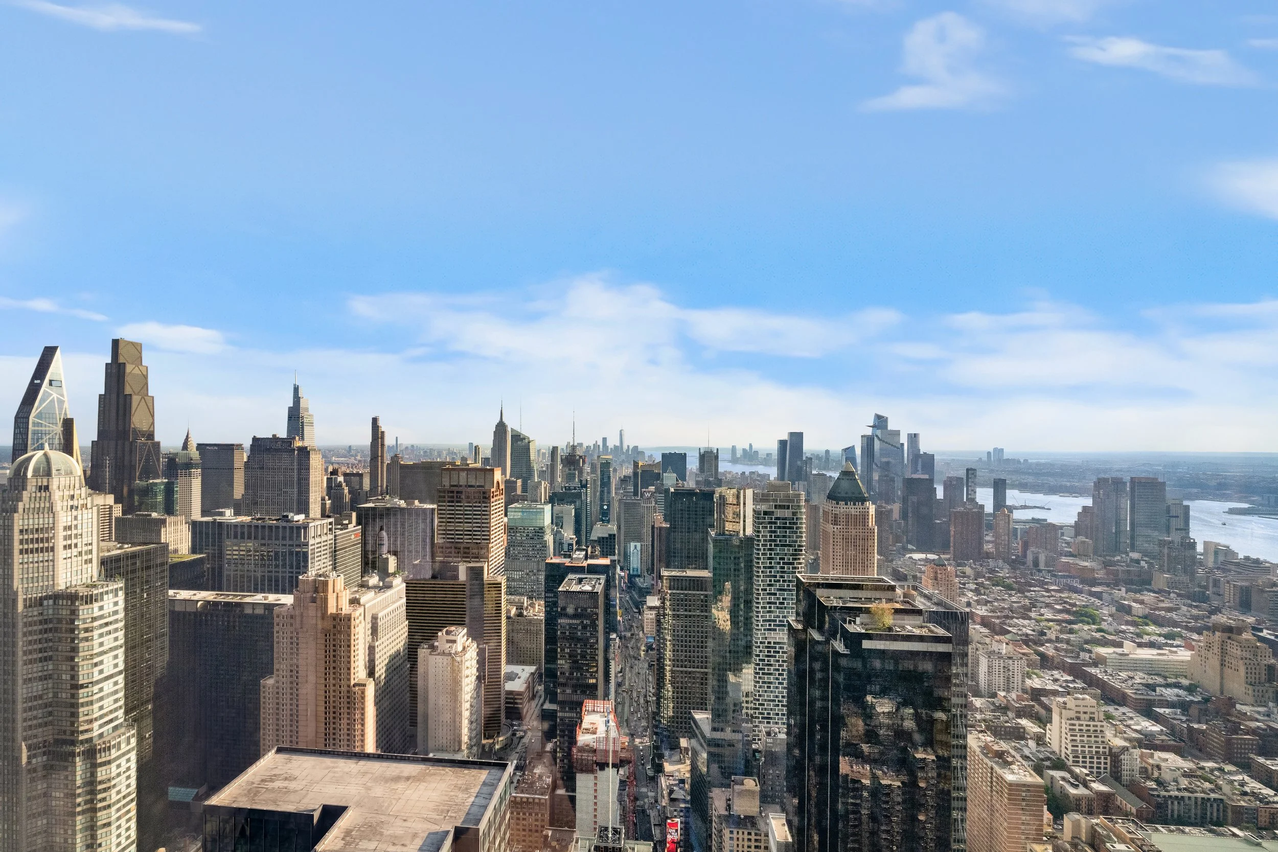 A city skyline featuring tall skyscrapers under a partly cloudy blue sky.
