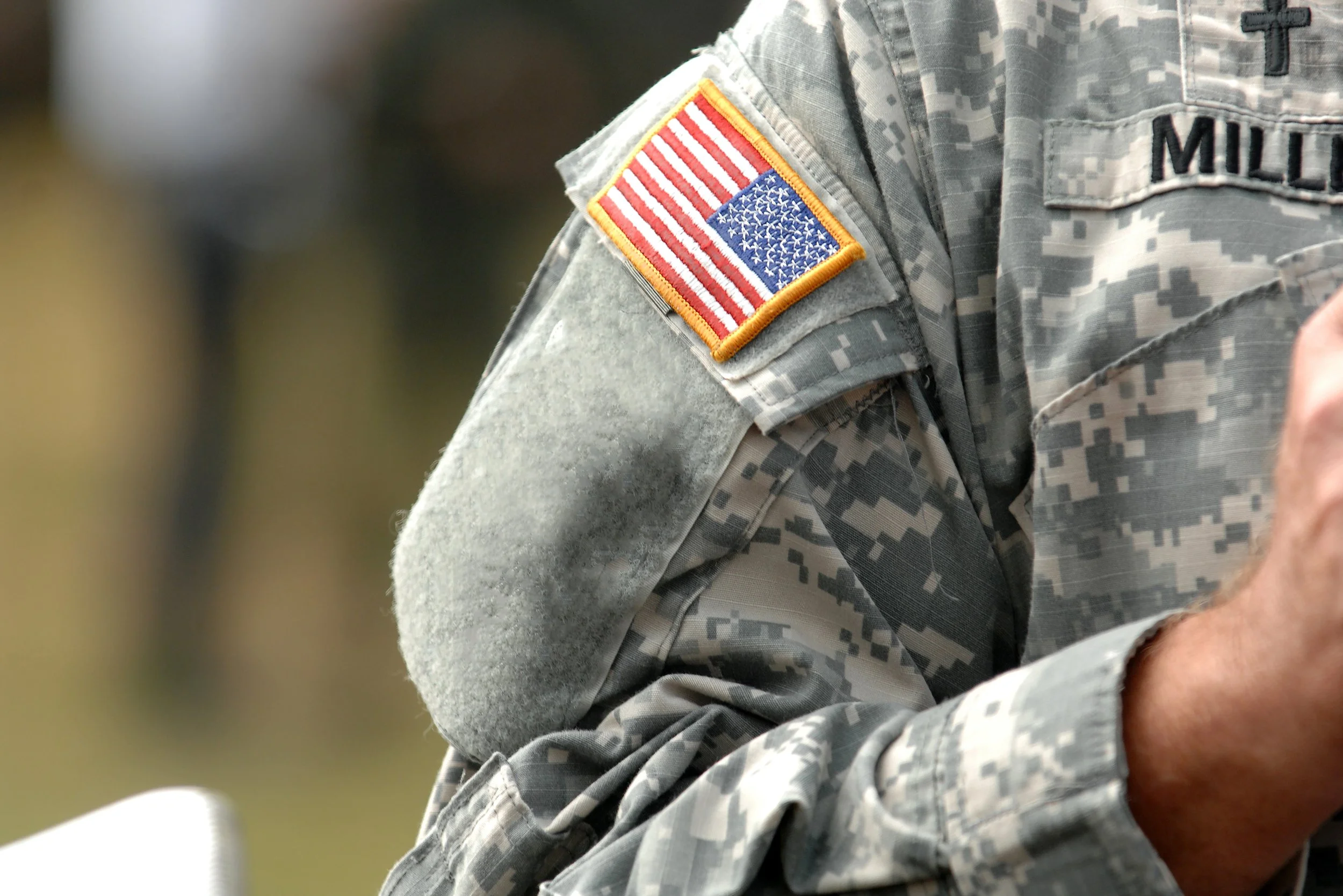 Close-up of a person in military uniform with an American flag patch on the shoulder.
