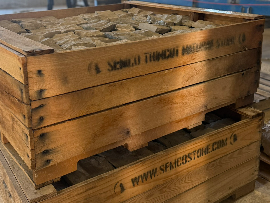 Wooden pallets filled with stone pieces in an indoor warehouse.