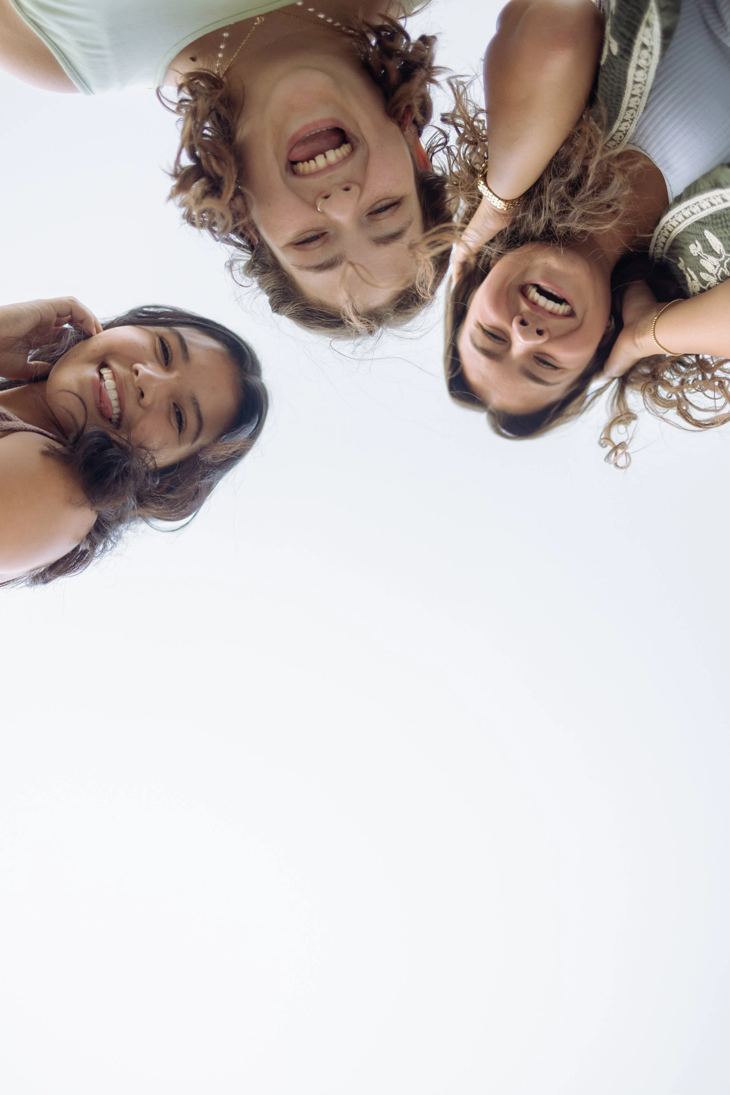 Four women are looking down at the camera, smiling and laughing.
