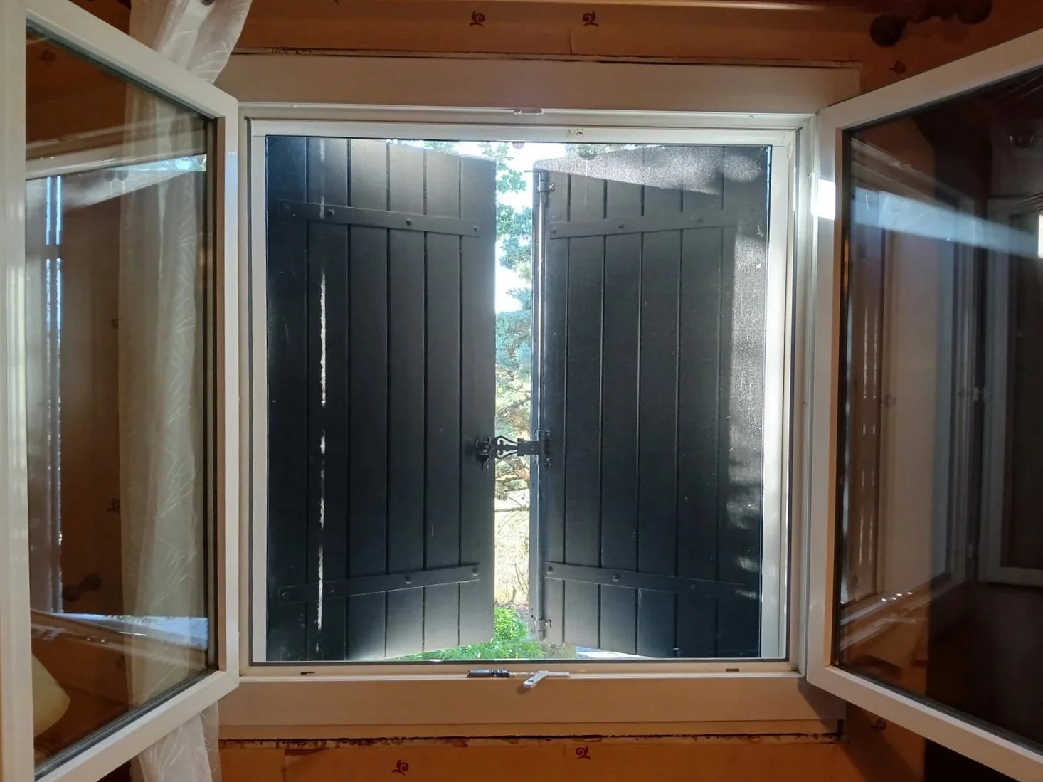 Moustiquaire posée sur une fenêtre avec des volets clos.