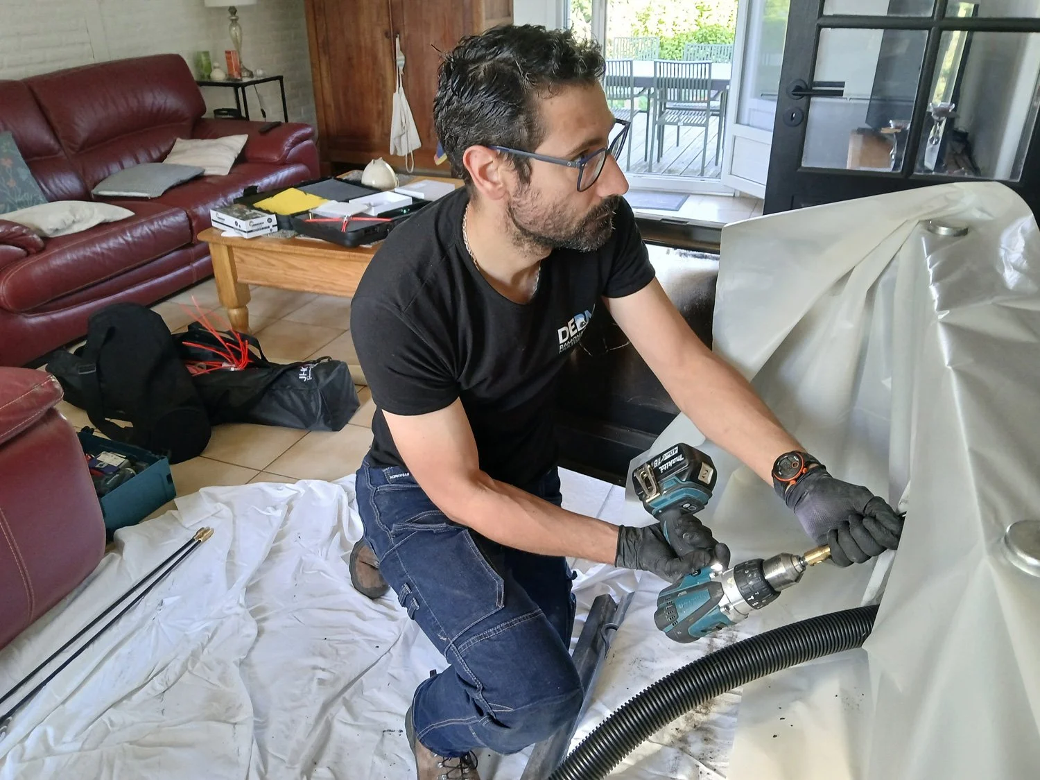 Un homme fait une intervention de ramonage sur un site protégé d'une bâche blanche