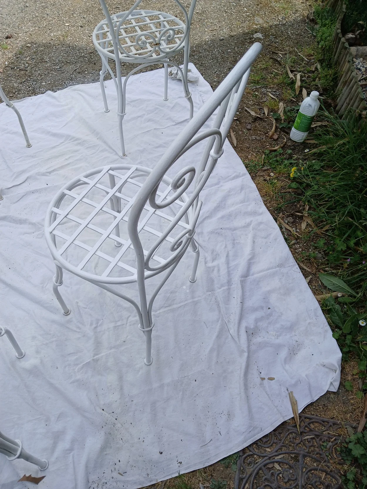 Chaises en métal blanc disposées sur une bâche blanche dans le jardin