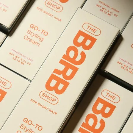 Boxes of BARB Styling Cream with orange text on white packaging.