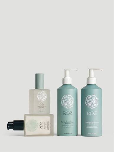 Four hair care products from ROZ including two bottles with pumps and two smaller bottles or tubes, all in light pastel colors with white floral designs.