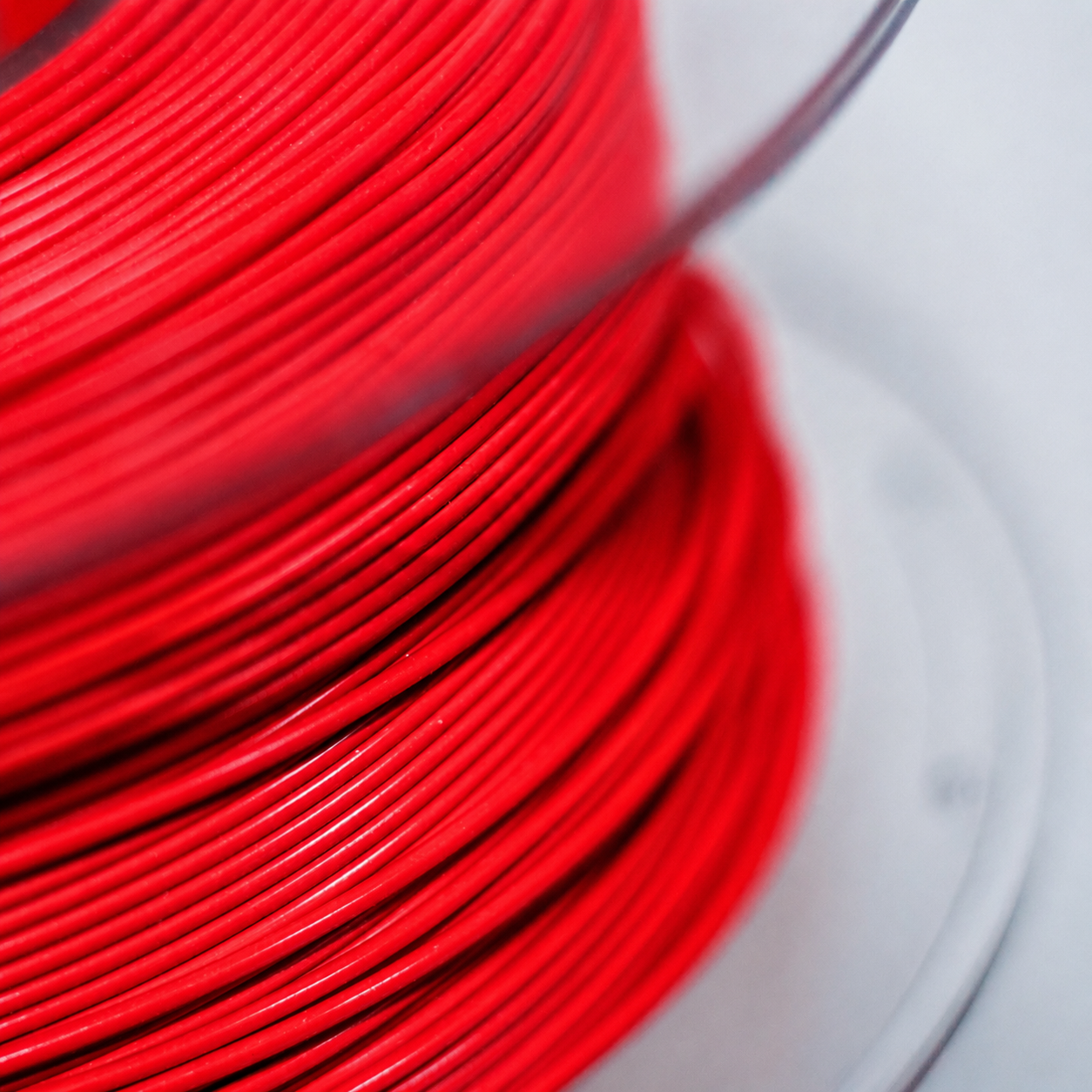 Close-up of a spool of red metering wire wound around a spool.