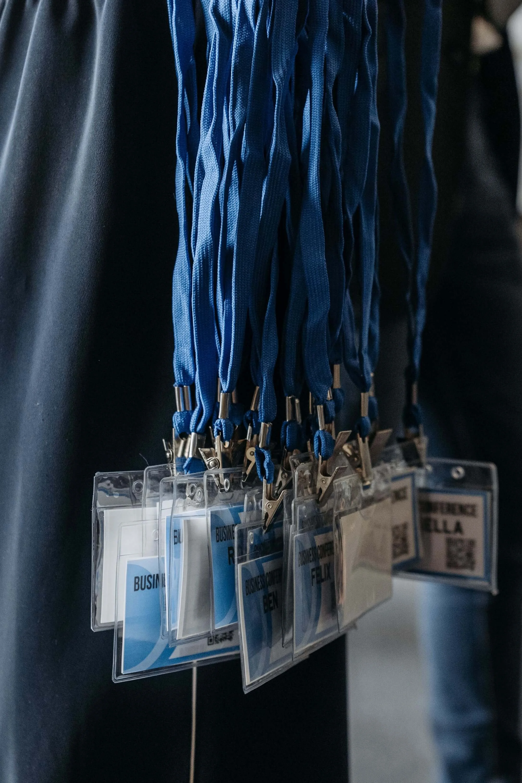 A person wearing a black shirt with a badge holder containing multiple identification cards hanging from their pocket.