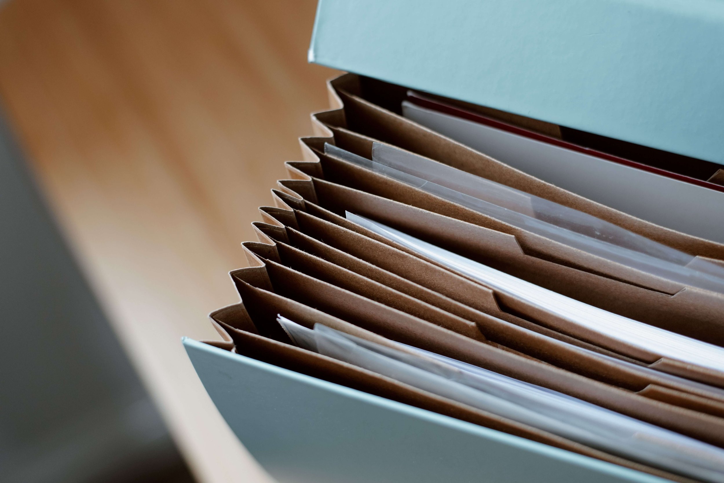 Close-up of paper folders or files inside a light blue storage box.