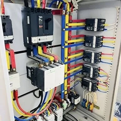Electrical control panel with circuit breakers, relays, and colorful wiring.