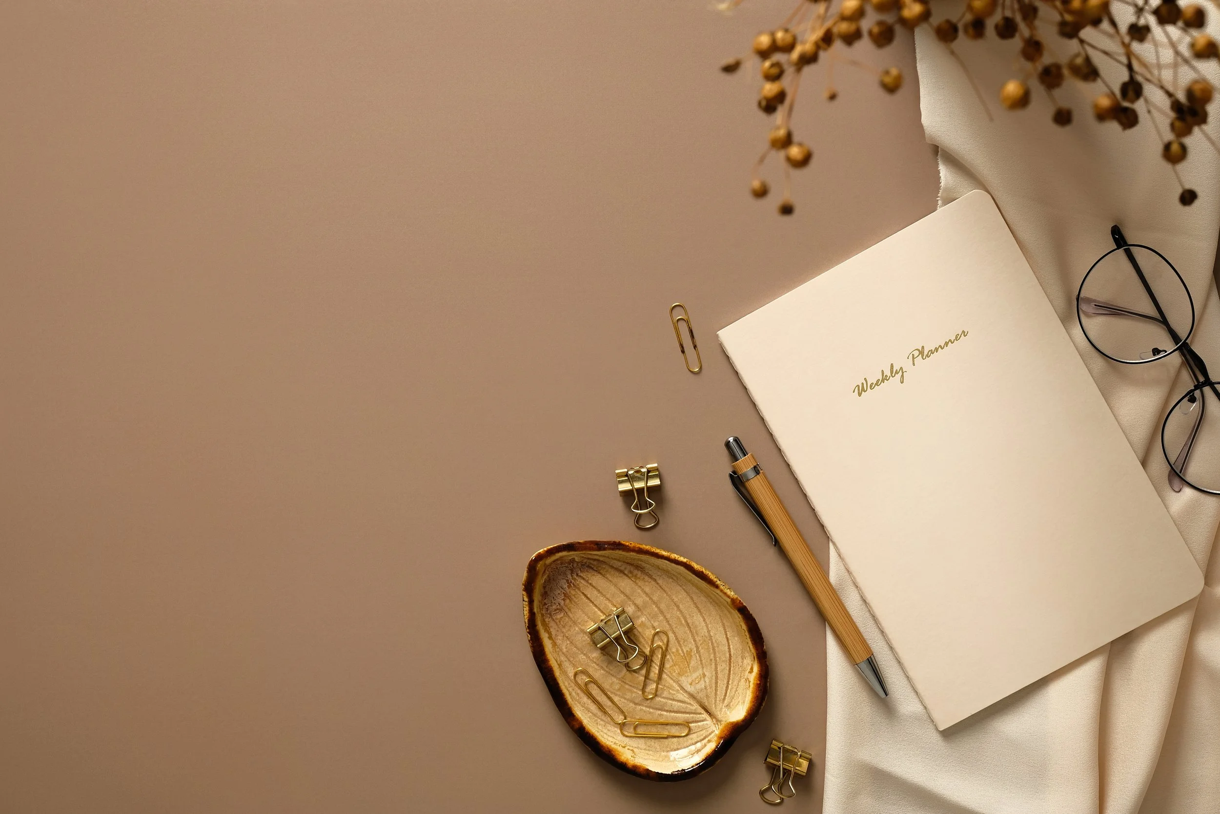 Daily planner on tan background with paperclips in a holder