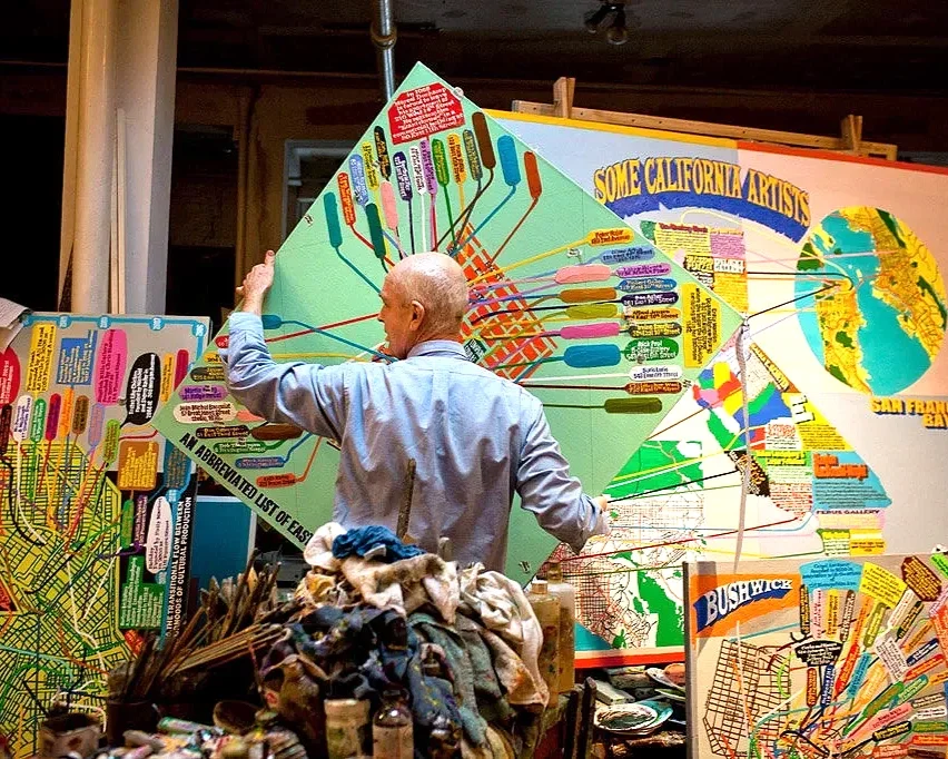 Loren Munk moving an East Village map painting in his studio, surrounded by other works in progress and artist materials