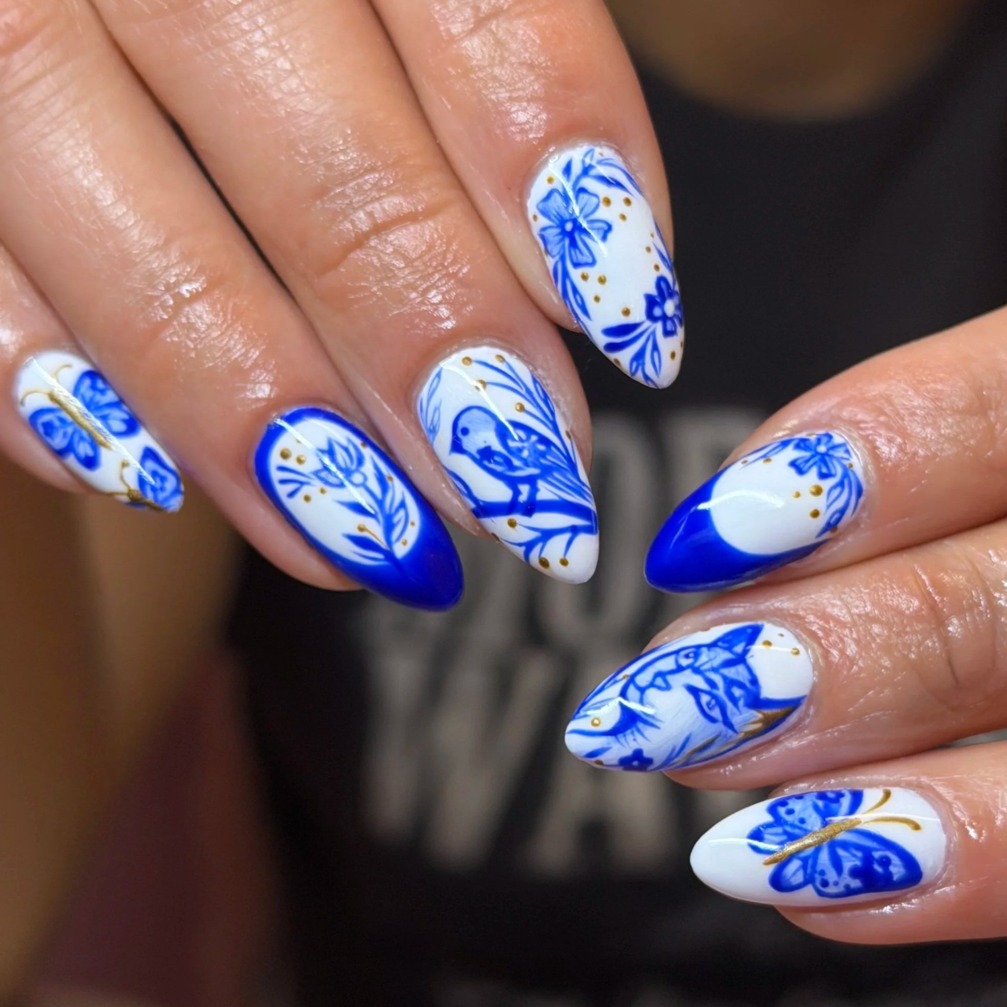 Close-up of a hand with decorated blue and white floral nail art.