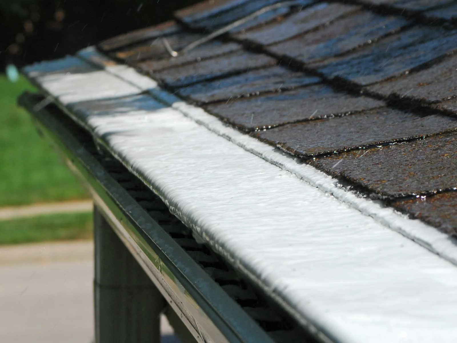 Rain falling on a tiled roof, with water flowing down the edge, creating a wet surface.