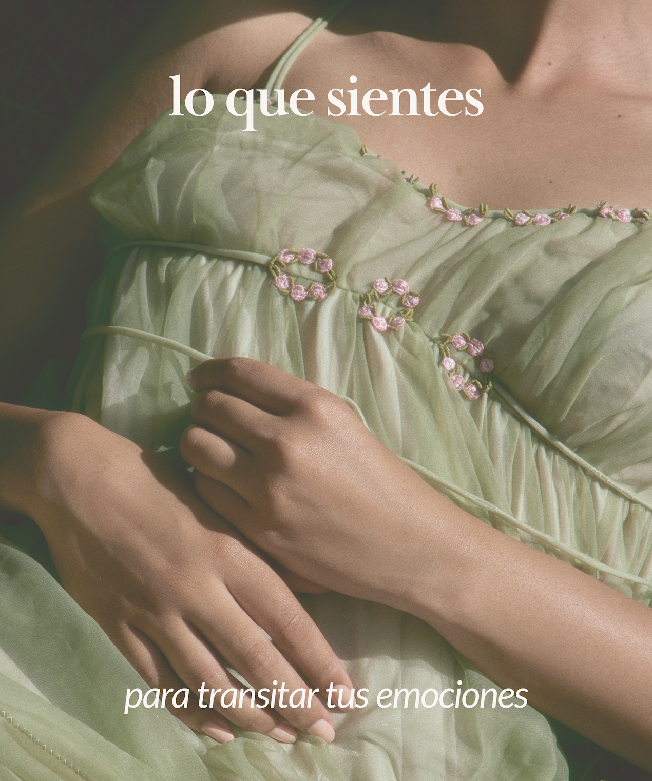 Manos sobre un vestido de tela ligera de color verde con detalles de flores rosadas y verdes, con el texto 'lo que sientes para transitar tus emociones'.