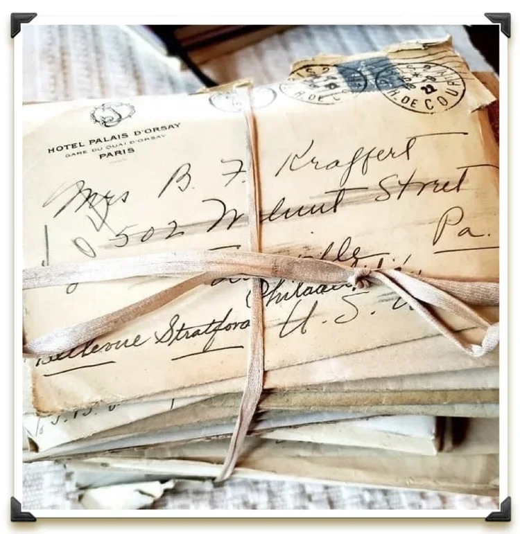 A stack of old, handwritten letters tied with a ribbon, with some addresses and stamps visible.