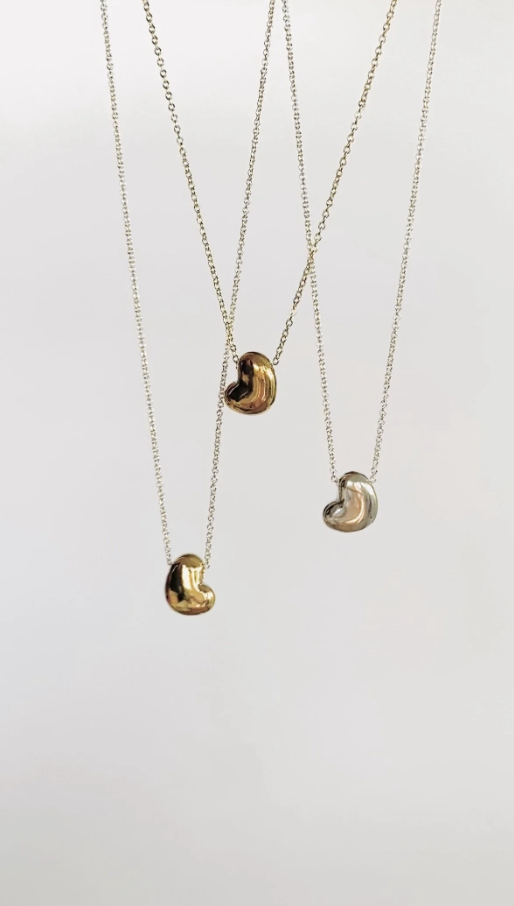 PAVA ATELIER | JEWELRY DESIGN | Four necklaces with irregularly shaped metallic pendants hanging from delicate chains, with two pendants in gold and two in silver.
