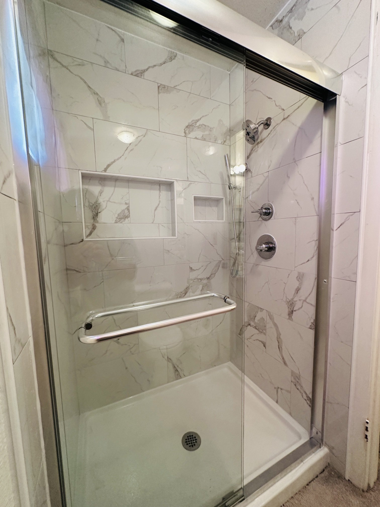 Custom tile shower remodel by TRI Construction Sacramento — marble tile, frameless glass door, built-in niche